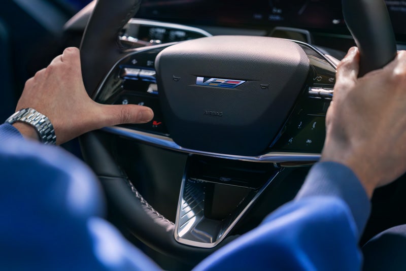 Close-up of a Man About to Press the V-Button on the 2026 OPTIQ-V Steering Wheel | Brotherton Cadillac NW in SHORELINE WA